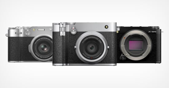 Three Fujifilm digital cameras are displayed side by side, with the two on the left featuring attached lenses and a vintage-style silver and black design, while the camera on the right is black and lacks a lens, revealing the sensor.