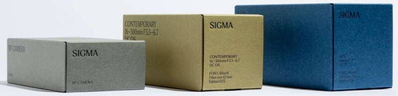 Three SIGMA camera lens boxes of different sizes and colors—gray, khaki, and blue—are lined up in a row against a plain white background. Each box displays branding and lens specifications.