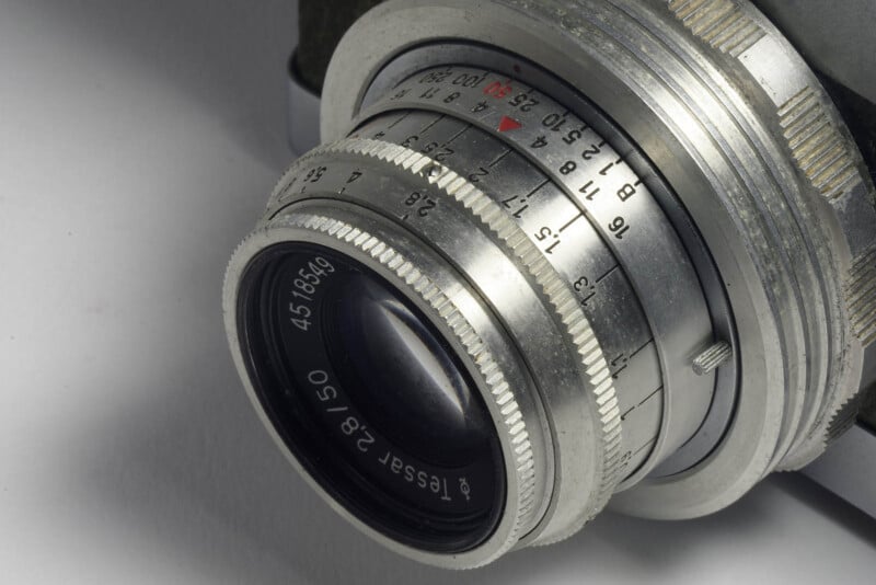 Close-up of a vintage Tessar 2.8/50 camera lens, showing detailed focus and aperture markings on the metal ring.